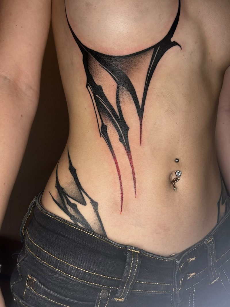 Large abstract blackwork with red accents from the underbust to the hip