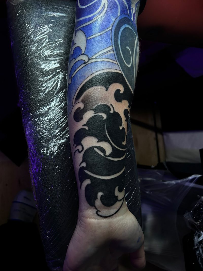 Japanese-style blackwork waves on the forearm