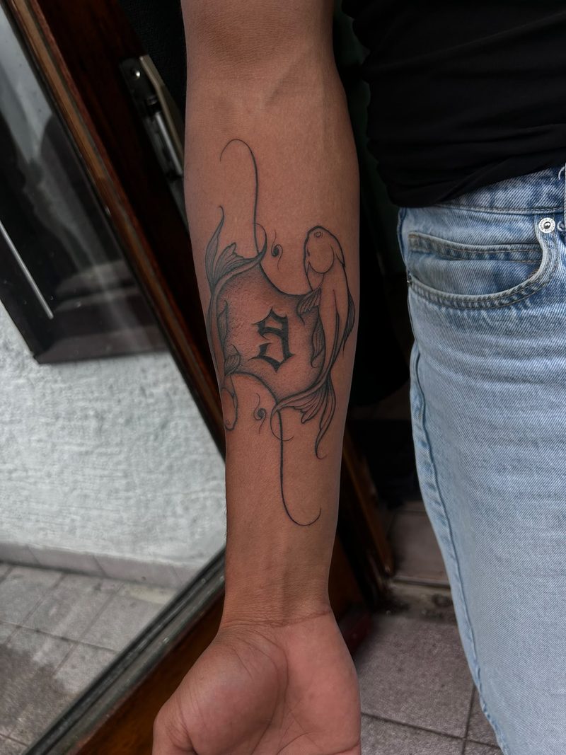 Two koi fish with an initial in fine line on the forearm